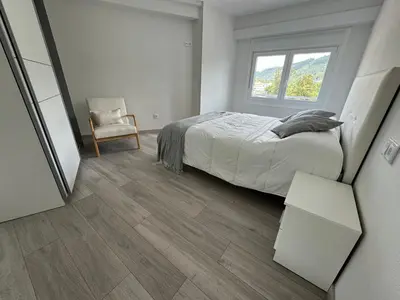 a bedroom with a bed and a chair and a window at Oktheway Caldas Centro in Caldas de Reis