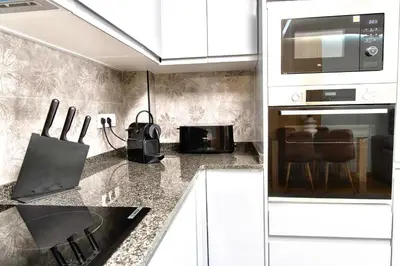 a kitchen with white cabinets and a laptop on a counter at Rosalia Park by Lugo Collection in Lugo