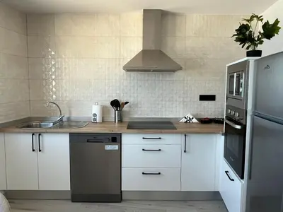a kitchen with white cabinets and a stainless steel refrigerator at Apartamento BURELA PALOMA PLAYA in Burela de Cabo