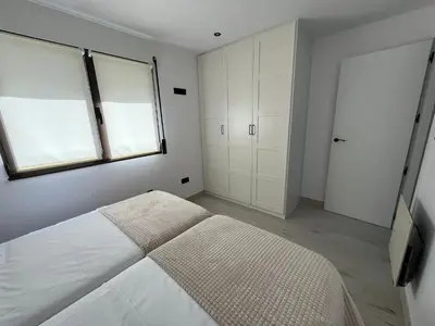a white bedroom with a bed and a window at Apartamento BURELA PALOMA PLAYA in Burela de Cabo