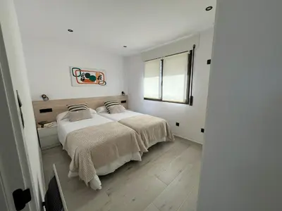 a white bedroom with a bed and a window at Apartamento BURELA PALOMA PLAYA in Burela de Cabo