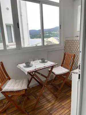 a table and two chairs in a room with windows at Covas Home in Viveiro