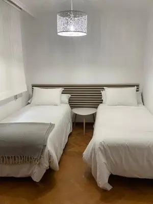 a bedroom with two beds and a table and a chandelier at Covas Home in Viveiro