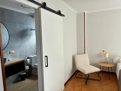 a bathroom with a sliding door and a chair at Covas Home in Viveiro