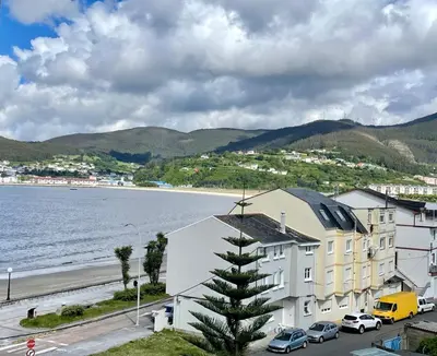 a view of a beach and a building with a tree at Covas Home in Viveiro