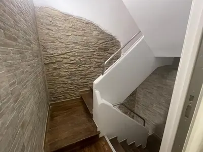 a staircase with a stone wall and wooden floors at Céntrico apartamento muralla 2 in Lugo