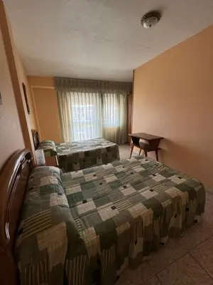 a hotel room with two beds and a desk at Hostal Pensión LA TORRE in Fabero