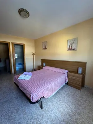 a bedroom with a bed with a pink comforter at Hostal Pensión LA TORRE in Fabero