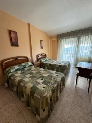 a hotel room with two beds and a table at Hostal Pensión LA TORRE in Fabero
