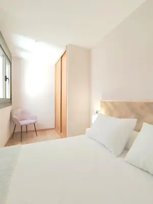 a bedroom with a white bed and a chair at Viveiro Centro con parking in Viveiro
