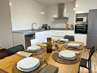 a kitchen with a wooden table with plates and glasses at Casa BastiAna in Carracedo