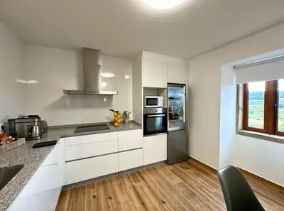 a kitchen with white cabinets and a large window at Casa BastiAna in Carracedo
