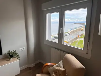 a room with a chair and a window with a view of the ocean at Piso a pie de playa in Burela de Cabo