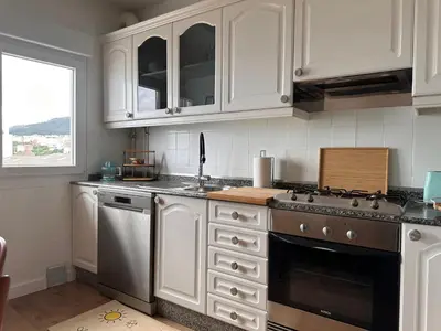 a kitchen with white cabinets and a stove top oven at Piso a pie de playa in Burela de Cabo