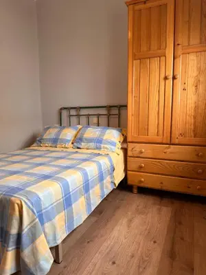 a bedroom with a bed and a wooden cabinet at Piso a pie de playa in Burela de Cabo