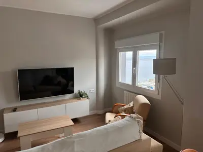 a living room with a couch and a tv and a window at Piso a pie de playa in Burela de Cabo