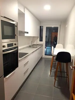 a kitchen with white cabinets and a table with chairs at Taboada Sacra Home in Taboada