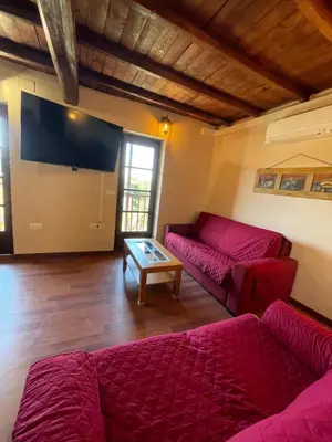 a living room with red couches and a flat screen tv at Alojamiento bodega LOF in Valtuille de Abajo