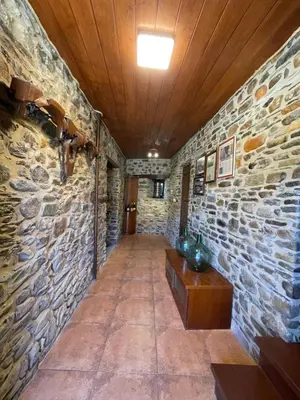 a hallway with a stone wall and a wooden ceiling at Alojamiento bodega LOF in Valtuille de Abajo