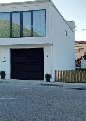 a white building with a large garage at Casa Tome A Teixeira - Ribeira Sacra in Teixeira