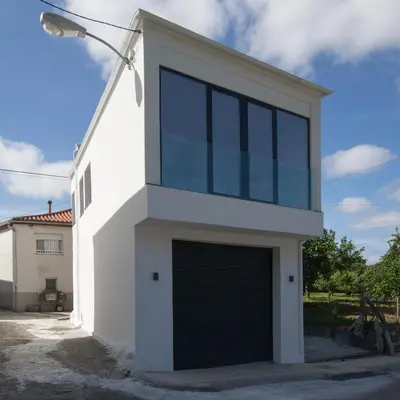 a white house with a garage at Casa Tome A Teixeira - Ribeira Sacra in Teixeira