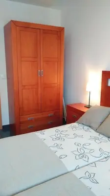 a bedroom with a bed and a wooden cabinet at Piso Encanto Palmeiro in Jove