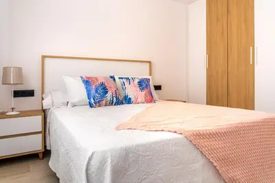 a bedroom with a white bed with a wooden cabinet at Maijo Burela Playa in Burela de Cabo