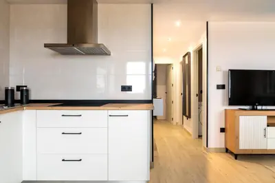 a kitchen with white cabinets and a flat screen tv at Maijo Burela Playa in Burela de Cabo