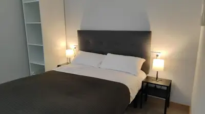 a bedroom with a bed with two lamps on tables at LAR de Yago - Habitación Ribadeo in Ribadeo