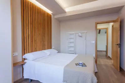 a bedroom with a white bed with a book on it at Apartamentos Rurales TIN TURISMO in Santa Eulalia de Oscos