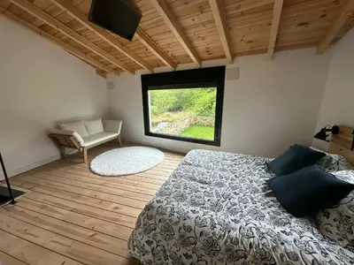 a bedroom with a bed and a chair and a window at Casa Fernanda-Ribeira Sacra in Covas
