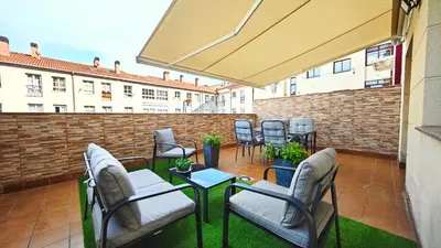a patio with chairs and tables and a brick wall at Piso céntrico Santiago de Compostela con terraza y parking in Santiago de Compostela
