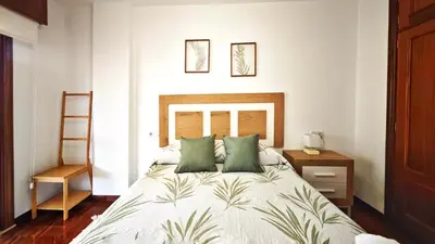 a bedroom with a bed with green pillows and a ladder at Piso céntrico Santiago de Compostela con terraza y parking in Santiago de Compostela