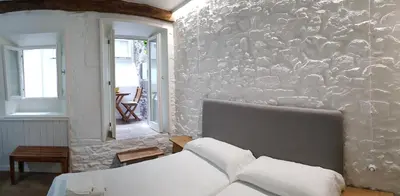 a bedroom with a stone wall with a bed at Pensión con Encanto San Martiño Pinario in Santiago de Compostela