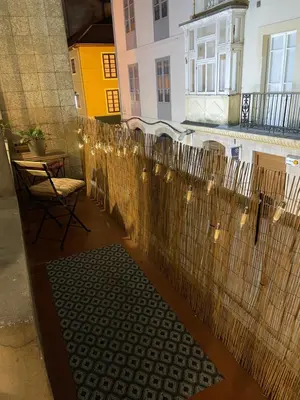 a balcony with a table and a chair and lights at Alojamiento D'Moda in Ribadeo