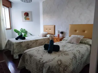 a bedroom with two beds with a person sitting on the bed at Apartamento Xaquina in Melide