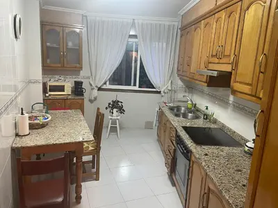a kitchen with wooden cabinets and a counter top at Apartamento Xaquina in Melide