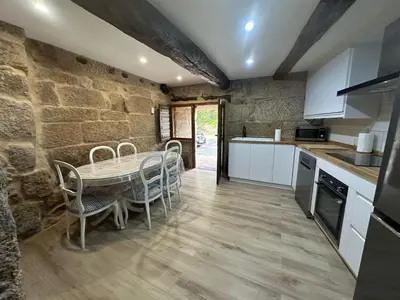 a kitchen with a table and chairs and a stone wall at Casa de Lucinda-Ribeira Sacra in Covas