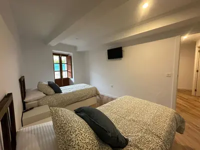 a bedroom with two beds and a tv on the wall at Casa de Lucinda-Ribeira Sacra in Covas