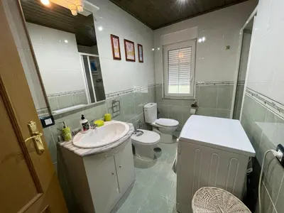 a bathroom with a sink and a toilet and a mirror at Apartamento La Veiga in Cerredo