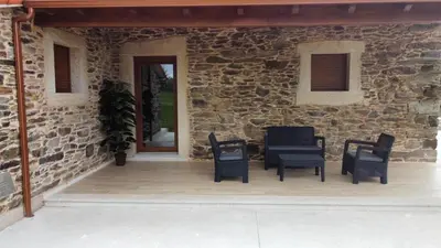 a patio with chairs and tables and a stone wall at Eira do Xastre in Brocos