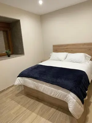 a bedroom with a large bed with a blue blanket at Eira do Xastre in Brocos