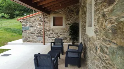 a patio with chairs and a stone wall at Eira do Xastre in Brocos