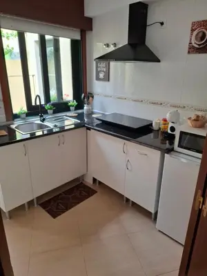 a kitchen with white cabinets and a sink and a stove at Piso DJC in O Pedrouzo
