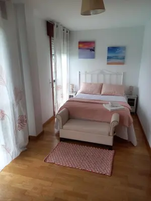 a white bedroom with a bed and a rug at Piso DJC in O Pedrouzo