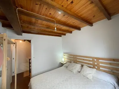 a bedroom with a white bed and wooden ceilings at Casa duples junto playa Cubelas in San Ciprián