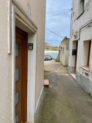 a door to a building with a car parked on a street at Casa duples junto playa Cubelas in San Ciprián