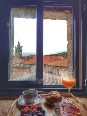 a table with food and a drink and a window at Luz do Sil in Ourense