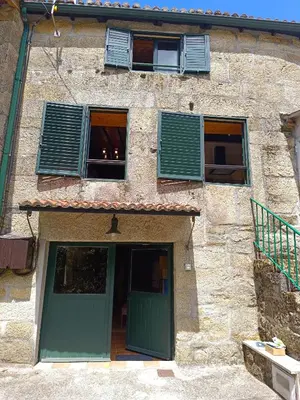 a building with a green door and two windows at Luz do Sil in Ourense