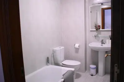a white bathroom with a toilet and a sink at Fogar da Fraga in Caldas de Reis